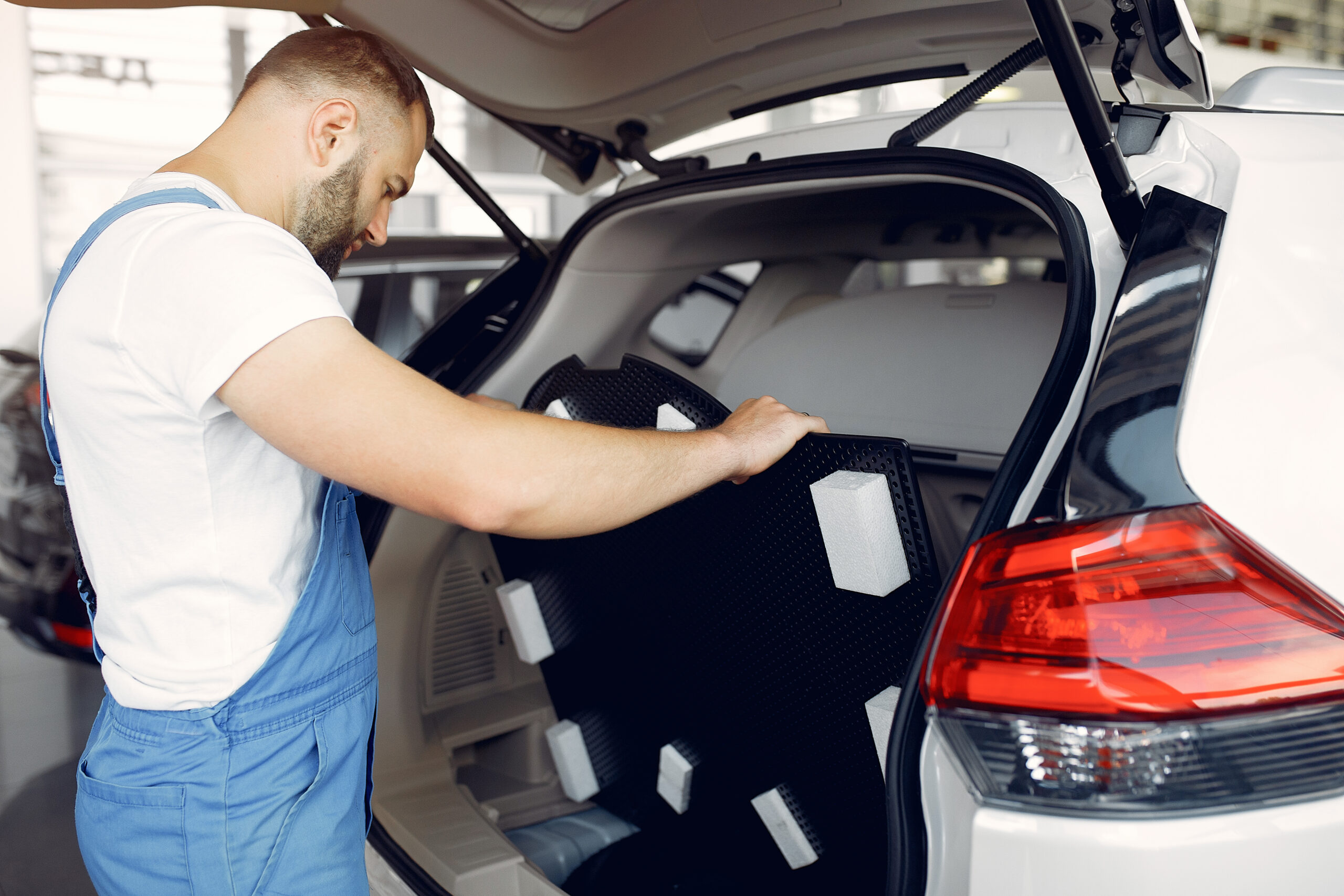 Wrker in a car salon. Expert checks the car. Man in a blue uniform.